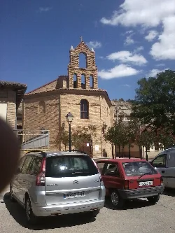 Edificio de ladrillo con campanario en el centro de Arguedas.