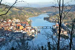 View of Orio's harbor and river with green hills in the background.