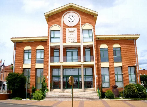 Edificio del ayuntamiento con fachada de ladrillo, reloj y escaleras en la entrada.