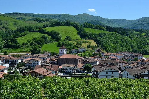 View of a town with houses and a church in a valley surrounded by mountains.