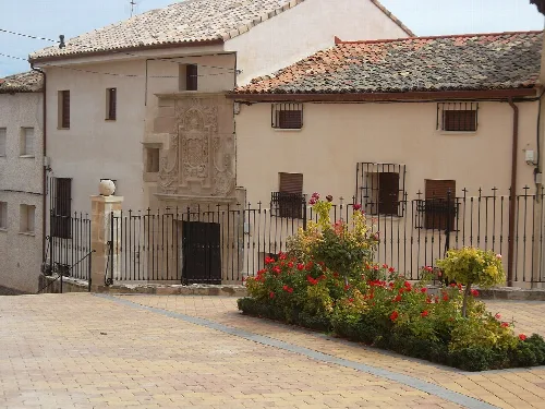 Houses in Millana with coats of arms and a flower garden.