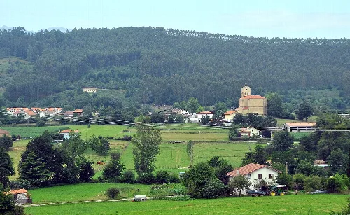 Paisaje de Rasines con casas, árboles y colinas verdes.