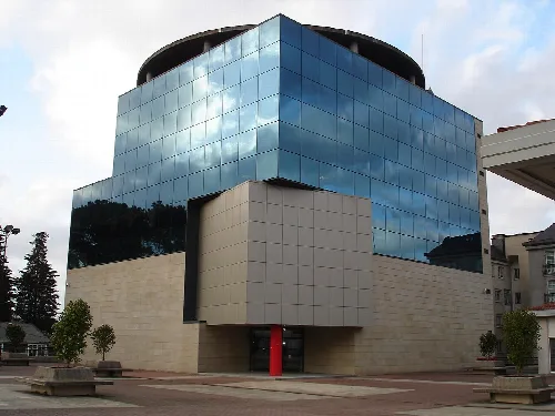 Multi-story building with blue glass facade and stone base.