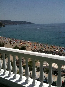 Playa de Nerja con sombrillas y mar en un día soleado.