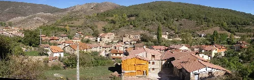 Landscape of houses on a hill with mountains in the background.