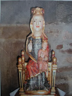 Statue of the Virgin of Areños indoors with stone walls.