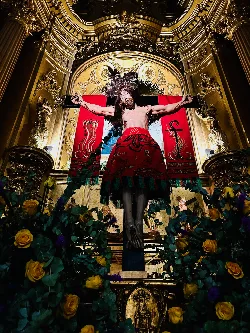 Statue von Jesus Christus in einer Kirche, umgeben von Blumen und goldener Dekoration.