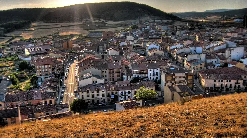 Luftaufnahme von Huerta de Rey mit Häusern, Straßen und Hügeln bei Sonnenuntergang.