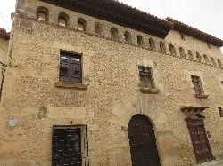 Stone building with windows and an arched door in Las Parras de Castellote.