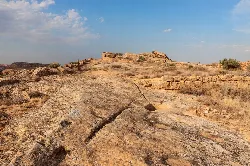 Rocas y canales en un paisaje seco con cielo azul y algunas nubes.