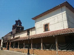 Fachada de una iglesia con torre y muro de ladrillo en Laguna de Negrillos.