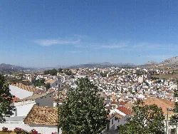 Vista de Colmenar con casas blancas y montañas en el fondo.