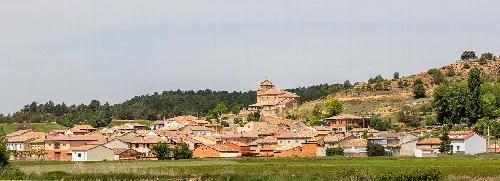 Häuser und eine Kirche auf einem Hügel in Valdenebro.