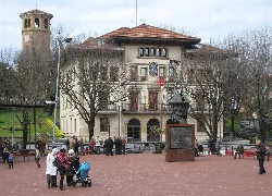 Plaza en Sestao con edificio del ayuntamiento y escultura de busto.