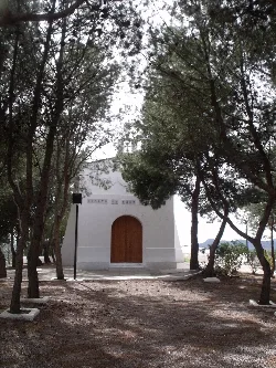 Small white hermitage among trees with dirt path in Casinos.
