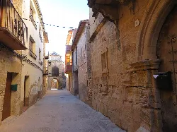 Narrow street with stone buildings and balconies in Cretas.