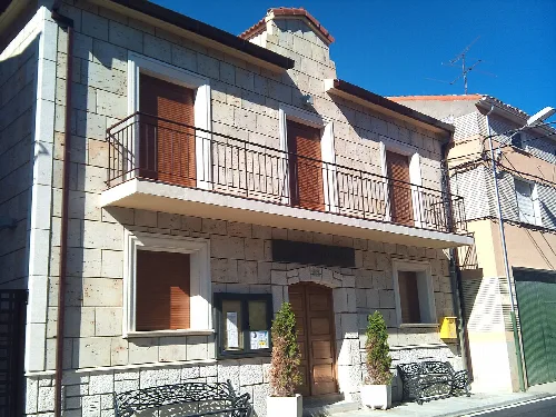Edificio del ayuntamiento con fachada de piedra y balcón en la planta superior.