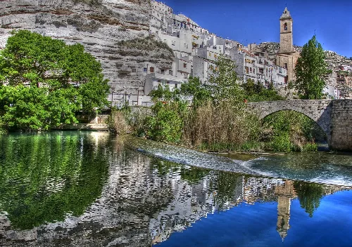 Casas blancas y una iglesia en Alcalá del Júcar junto al río.