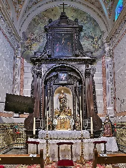 Holzaltar mit Gemälden und einer Marienfigur in der Kirche von Benacazón.