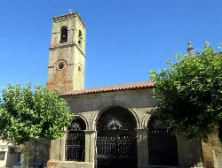 Glockenturm und Kirchenportal mit Bäumen an den Seiten.