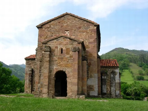 Iglesia de Santa Cristina de Lena en un paisaje rural con montañas verdes.