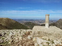 Mojón de piedra en la cima del Pico de el Terril con vista panorámica de montañas y llanuras.