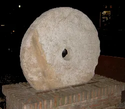 Old stone mill wheel on a brick base in Alhaurín de la Torre