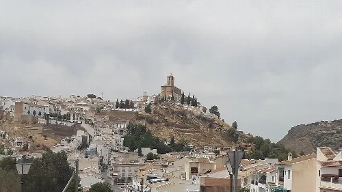 Panorámica de Iznájar con iglesia en la colina y casas blancas.