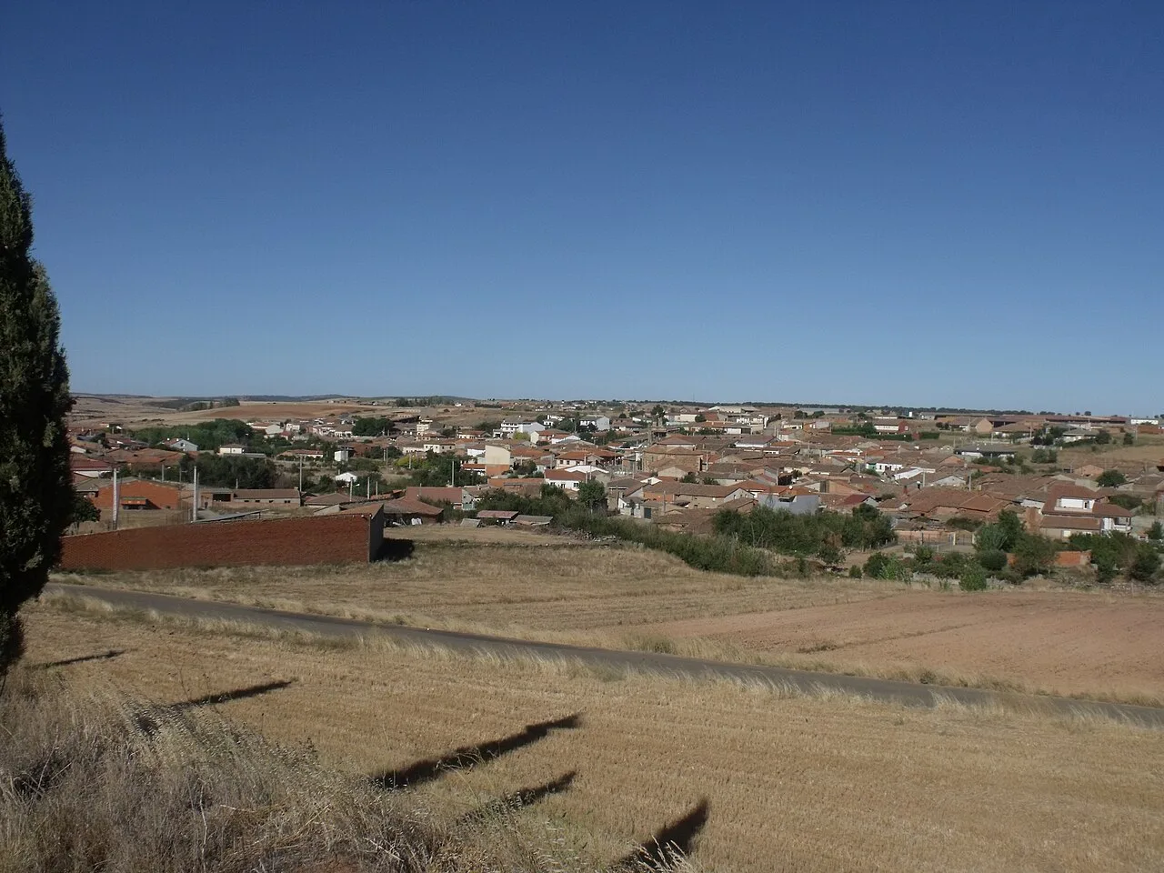 Vista de un pueblo con casas y campos en un paisaje abierto.