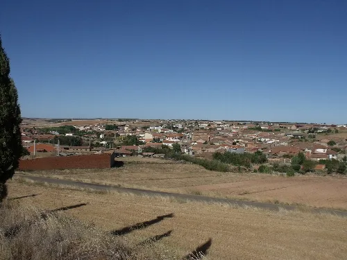 Blick auf ein Dorf mit Häusern und Feldern in einer offenen Landschaft.