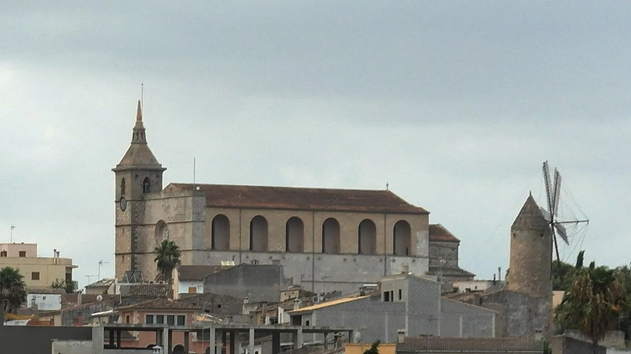 Kirche und Windmühle in Santa Margarita, Balearen, bei bewölktem Himmel.