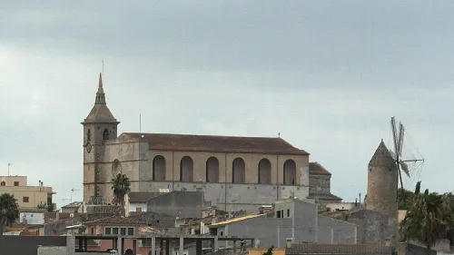 Iglesia y molino en Santa Margarita, Baleares, con cielo nublado.