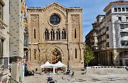 Stone church and plaza with stalls and people in Lleida.
