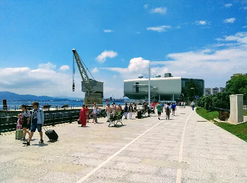 Meeresuferpromenade mit Menschen, Kran und Gebäuden in Santander.