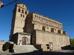 Church of Our Lady of the Assumption in Perdiguera, with tower and stone facade.