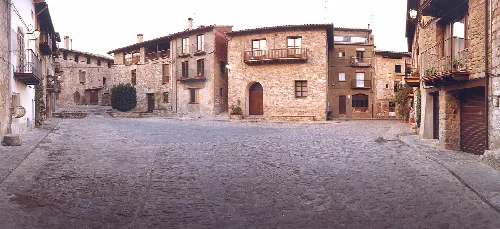 Fotografia de la Plaça del Gambeto de Riudaura i la façana de l'ajuntament del municipi al centre de la imatge.
