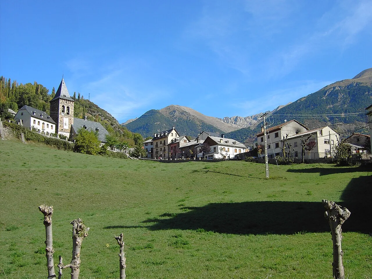 Panoramablick auf das Dorf Plan mit Kirche und Häusern im Bergtal.