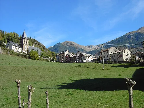 Panoramablick auf das Dorf Plan mit Kirche und Häusern im Bergtal.