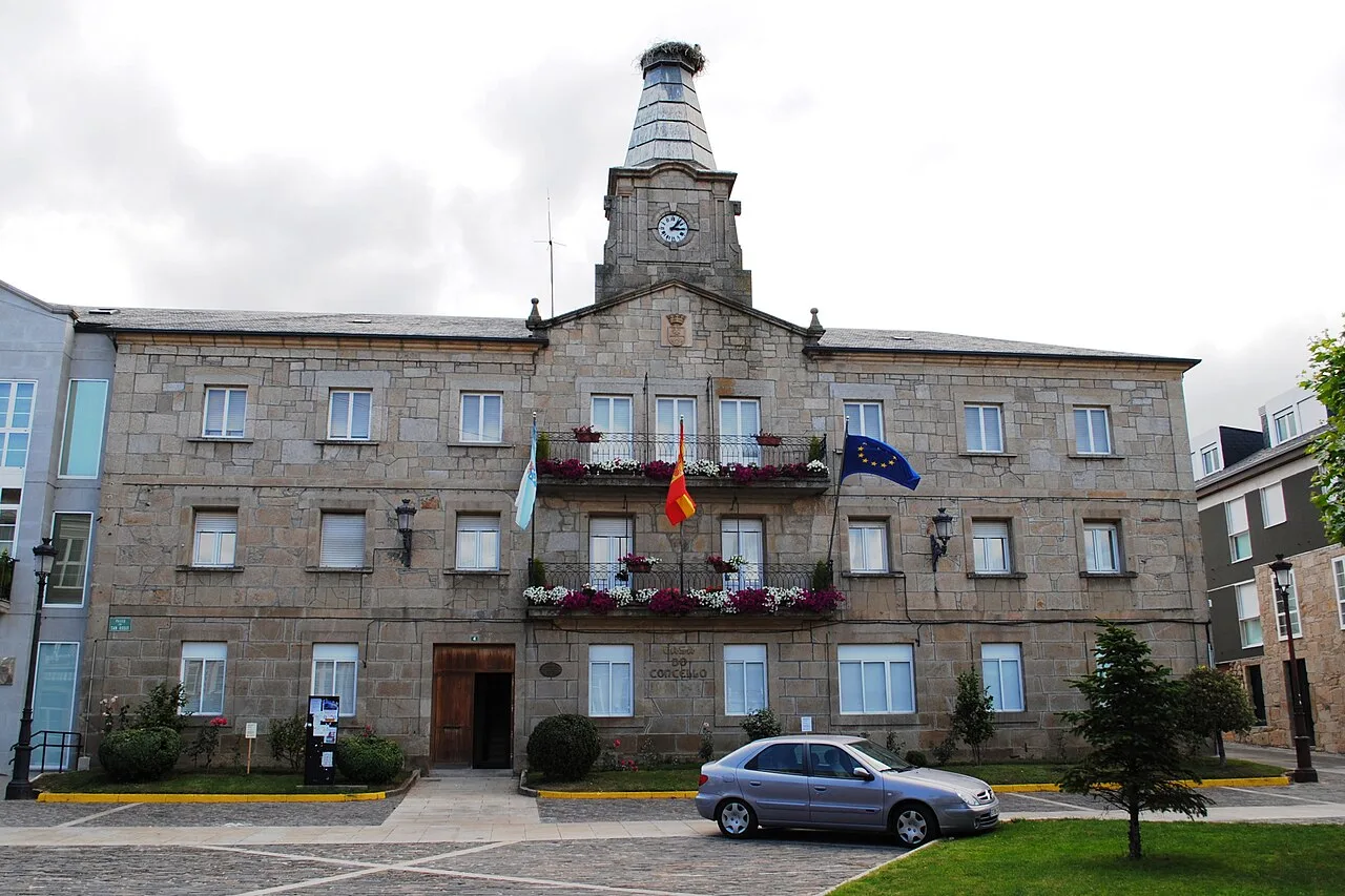 Edificio de piedra con banderas y reloj en la fachada.