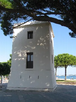Torre blanca en Cambrils con árboles y vista al mar.