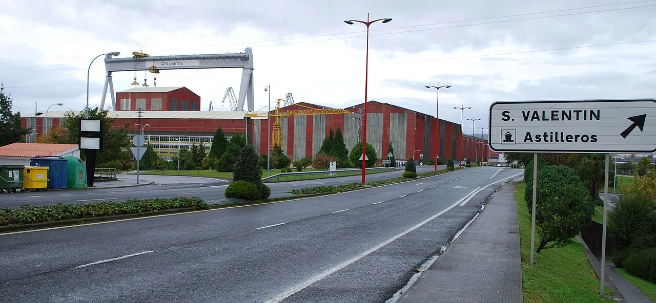 Straßenansicht mit Richtungsschild und Industriegebäude in Fene.