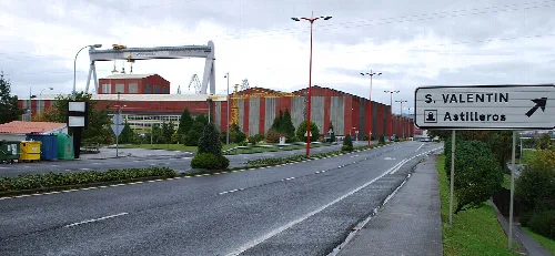 Street view with direction sign and industrial buildings in Fene.