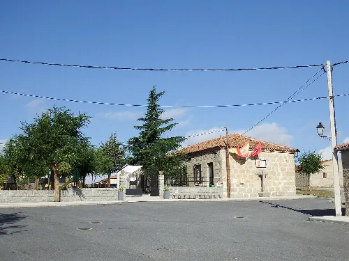 Platz mit Bäumen und Steinhaus in Narros del Puerto.
