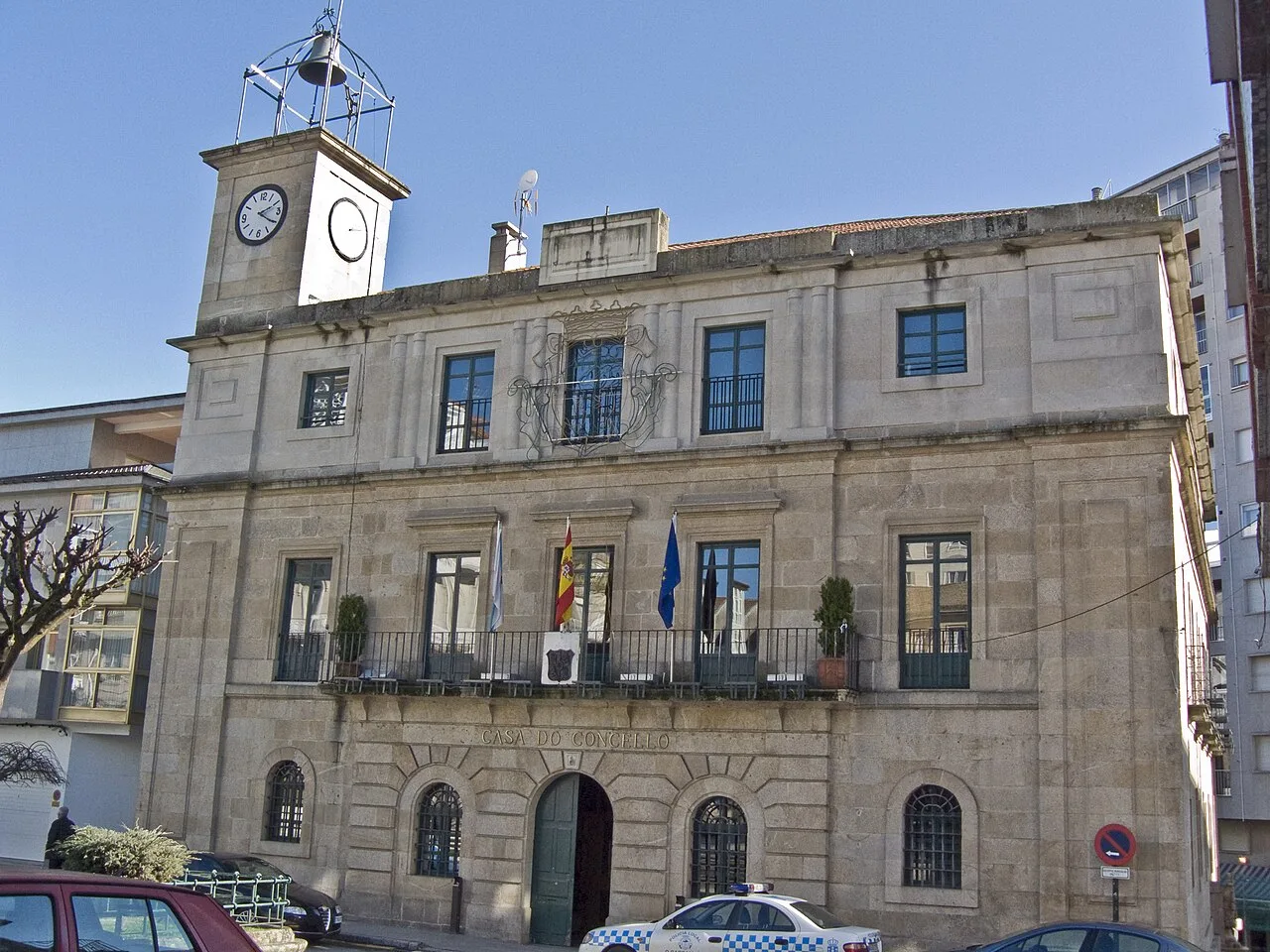 Steinernes Gebäude mit Uhr und Flaggen an der Fassade.