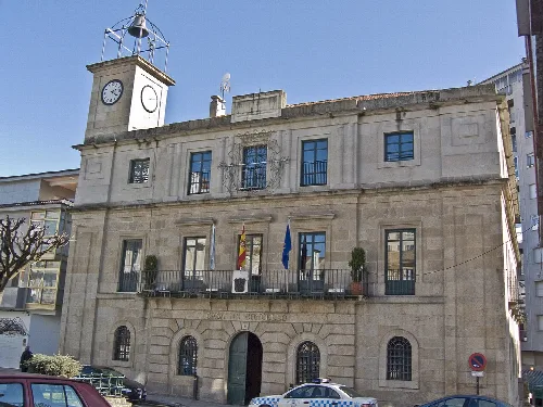 Steinernes Gebäude mit Uhr und Flaggen an der Fassade.