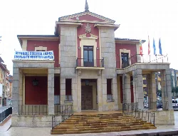 Edificio del ayuntamiento de Nava con escaleras y banderas.