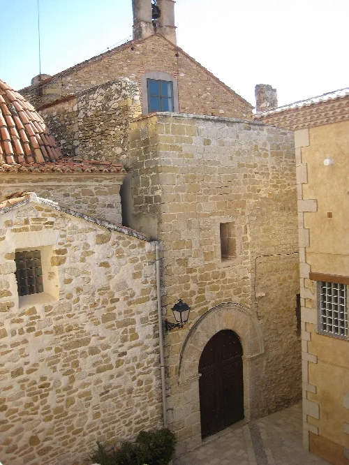 Stone facade of the church with an arched door in Cervera del Maestrat.