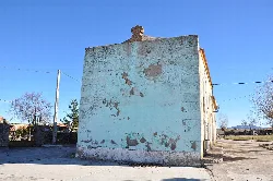 Building of pelota fronton in Gallegos de Sobrinos with worn walls and blue sky.