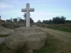 Stone cross with a cross on top, next to a rural road outside the town.