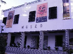 Fachada blanca del museo con carteles y ventanas con rejas.